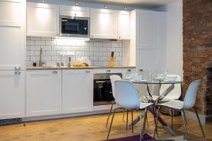cocina con armarios blancos, mesa y sillas en Pillo Rooms Serviced Apartments - Salford en Mánchester