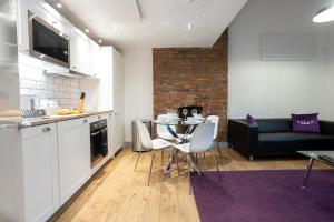 eine Küche und ein Wohnzimmer mit einem Tisch und einem Sofa in der Unterkunft Pillo Rooms Serviced Apartments - Salford in Manchester
