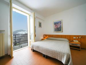 a bedroom with a bed and a large sliding glass door at Hotel Skilift - Dada Hotels in Frabosa Soprana