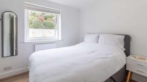a white bedroom with a bed and a window at Brand New Central Balcony Flat - Hastings Holidays in Hastings
