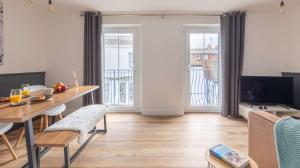 a living room with a wooden table and a dining room at Brand New Central Balcony Flat - Hastings Holidays in Hastings