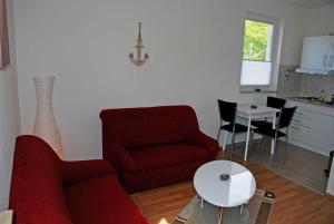 オストゼーバート・ゼリンにあるFerienhaus am Sonnenstegのリビングルーム(赤いソファ、テーブル付)