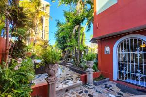 a red building with palm trees next to a street at Luxurious San Juan Villa with Pool - Walk to Beach! in San Juan