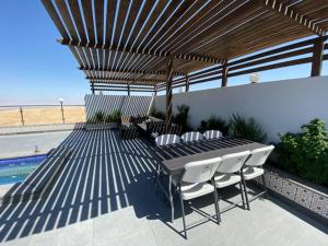 eine Terrasse mit einem Tisch und Stühlen unter einem hölzernen Baldachin in der Unterkunft Golden rays chalet in Madaba