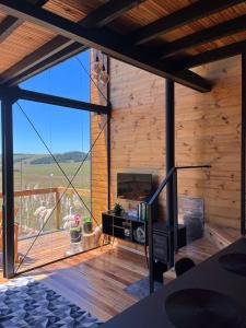 a living room with a fireplace and a large window at Cabana Cambará in Cambara do Sul