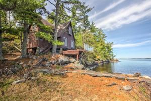 a house on the shore of a body of water at Cozy Stop Island Cabin with Boat Dock and Beach! in International Falls