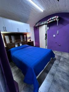 Un dormitorio con una cama azul y paredes moradas en Winewalker en Luján de Cuyo