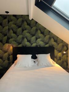 una camera da letto con un letto con cuscini bianchi di Logis Hotel du Maine a Laval
