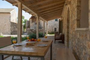 a wooden table with a bowl of fruit on a patio at AVLI - Tranquil stonehouse in Lefkada in Alexandros