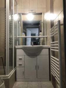 ein weißes Badezimmer mit einem Waschbecken und einem Spiegel in der Unterkunft Appartement cosy 100m plage de Pentrez in Saint-Nic