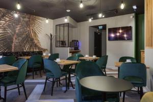 a dining room with tables and chairs and a wall at Logis Hotel du Maine in Laval
