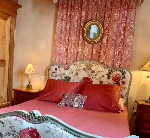 1 dormitorio con cama con almohadas rojas y espejo en Chambres d'hôtes La Borderie du Gô près de La Rochelle - Nieul, en Nieul-sur-Mer