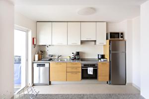 a kitchen with white cabinets and a stainless steel refrigerator at Welcome Cabanas Beach in Cabanas de Tavira