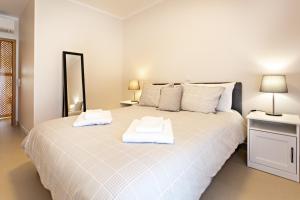 um quarto com uma grande cama branca com toalhas em Welcome Cabanas Beach em Cabanas de Tavira