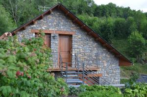 mały kamienny dom z drewnianymi drzwiami i schodami w obiekcie Ca del Pòsol w mieście Durro