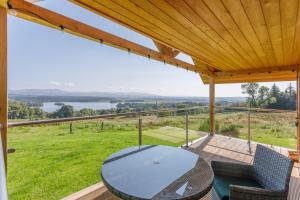 a patio with a table and chairs on a deck at Gamekeeper's Lodge- a cottage with a spectacular view in Port of Menteith