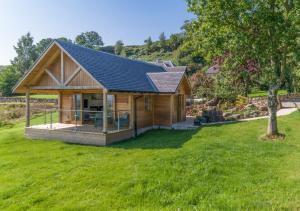a log cabin with a solar roof on a yard at Gamekeeper's Lodge- a cottage with a spectacular view in Port of Menteith