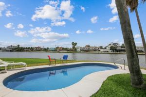 a swimming pool with chairs and a body of water at Prager Bay View in Galveston