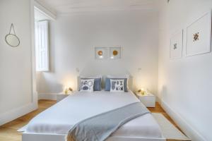 a white bedroom with a large bed with blue pillows at Modern Flat in Downtown Lisbon by LovelyStay in Lisbon