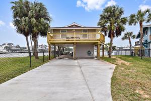 a large house with a balcony and palm trees at Prager Bay View in Galveston