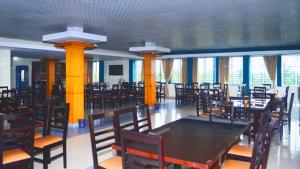una sala da pranzo con tavolo, sedie e finestre di Tea Heaven Resort a Sreemangal