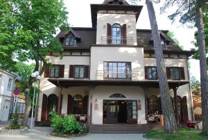 een groot wit huis met een balkon in een straat bij Villa Jurmala in Jūrmala