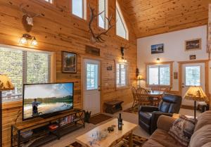 a living room with a large flat screen tv in a log cabin at Henrys Post by KABINO Dog Friendly Foosball Fire Pit SmartTV WiFi in Island Park