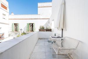 an outdoor balcony with chairs and an umbrella at El Erizo Apartamentos in Tarifa