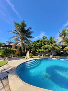 a swimming pool in front of a house with palm trees at Pousada Canoa Beach in Canoa Quebrada