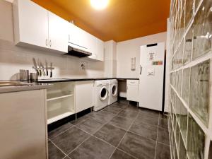cocina con armarios blancos, lavadora y secadora en Arc House Barcelona, en Barcelona