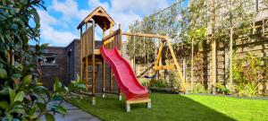 a playground with a red slide in a yard at Residence 5 in Ieper
