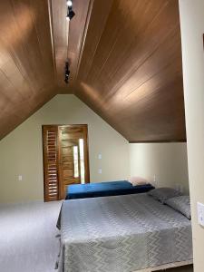 瓜拉米蘭加的住宿－Chalé Suíço，一间卧室设有一张带木制天花板的大床