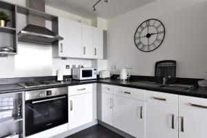 una cucina con armadi bianchi e un orologio sul muro di Stunning, 1-Bedroom Cosy Apartment in the Centre of Birmingham a Birmingham