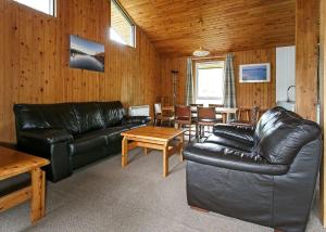 a living room with a black leather couch and a table at Lochearnhead Loch Side in Lochearnhead
