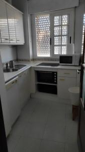 a white kitchen with a sink and a microwave at Vive Huelva MARINA WIFI 300 VFTHU01194 in Huelva