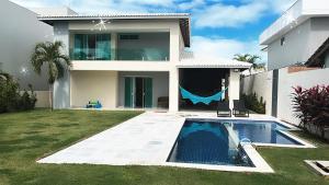 a villa with a swimming pool in front of a house at Venha se hospedar no Paraíso de Guarajuba in Camaçari