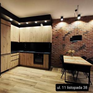a kitchen with a table and a brick wall at Asti Apartamenty Centrum Stargard in Stargard