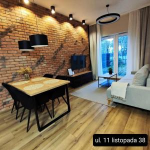 a living room with a table and a brick wall at Asti Apartamenty Centrum Stargard in Stargard