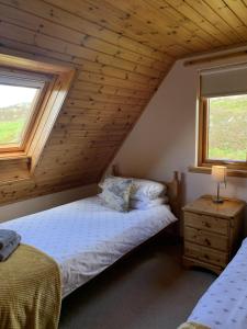 a bedroom with a bed and two windows at Thistle Cottage in Lairg