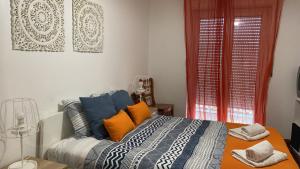 een slaapkamer met een bed met oranje en blauwe kussens bij Soul Surfer in Peniche