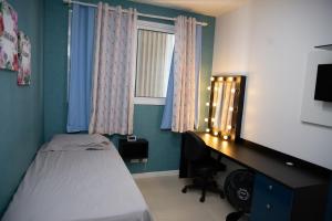 um quarto com uma cama, uma secretária e uma janela em Apto moderno próximo à Praia de Itaparica ES em Vila Velha