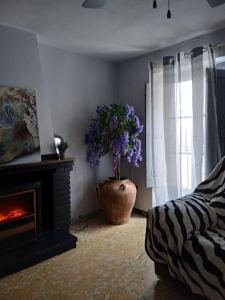 una sala de estar con chimenea y un jarrón de flores púrpuras en Casa Mónica, en Villalba dels Arcs