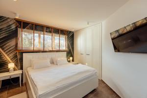 1 dormitorio con 1 cama blanca y TV en Stylish Mini-House with Garden & Beach, en Bijela