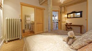 misia siedzącego na łóżku w sypialni w obiekcie Remparts de Riquewihr - Le Petit Ours w mieście Riquewihr