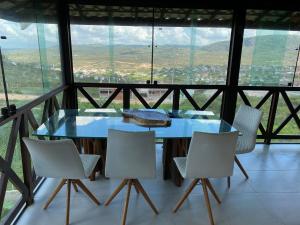 una mesa de cristal y sillas en una habitación con vistas en Recanto bosque da colina, en Gravatá