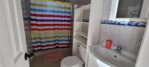 a bathroom with a rainbow shower curtain and a toilet at Club de Campo Alto Copiapó in Piedra Colgada