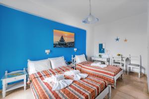 twee bedden in een kamer met een blauwe muur bij Villa George in Batsi