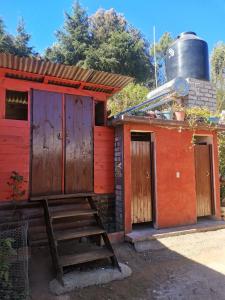 a small red building with a ladder and a barrel at Casa del bosque 