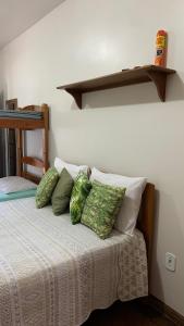 Una cama con almohadas verdes y blancas. en Suites Arraial do Cabo, en Arraial do Cabo