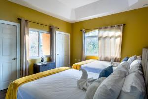 two beds in a bedroom with yellow walls and windows at BayWatch Villa - Montego Bay in Montego Bay +37 photos